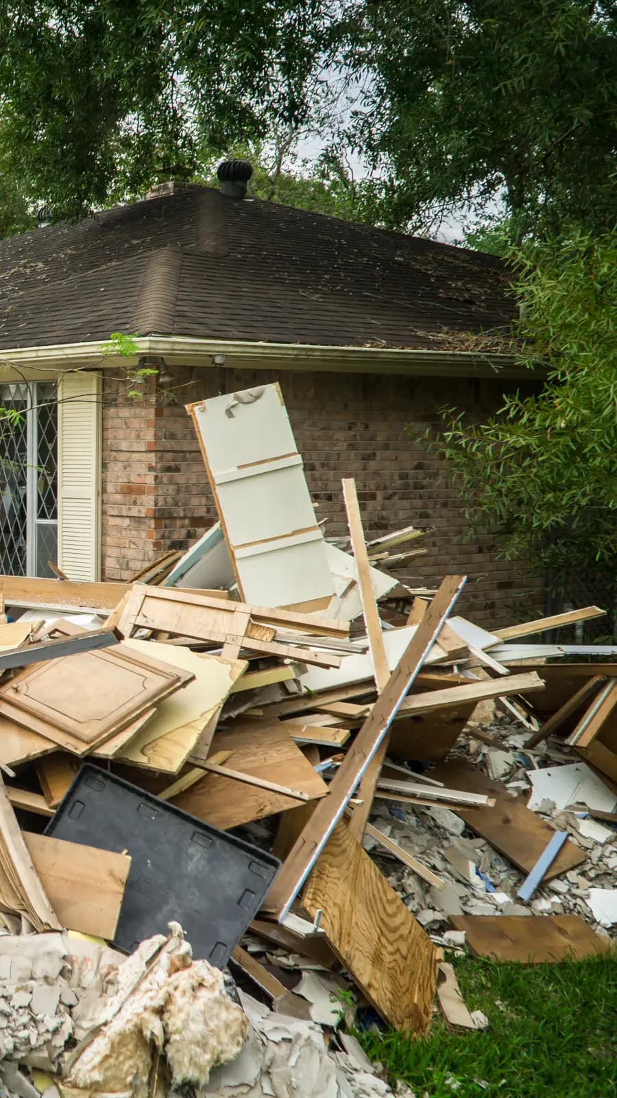 Image of a house with a pile of debris next to the garage